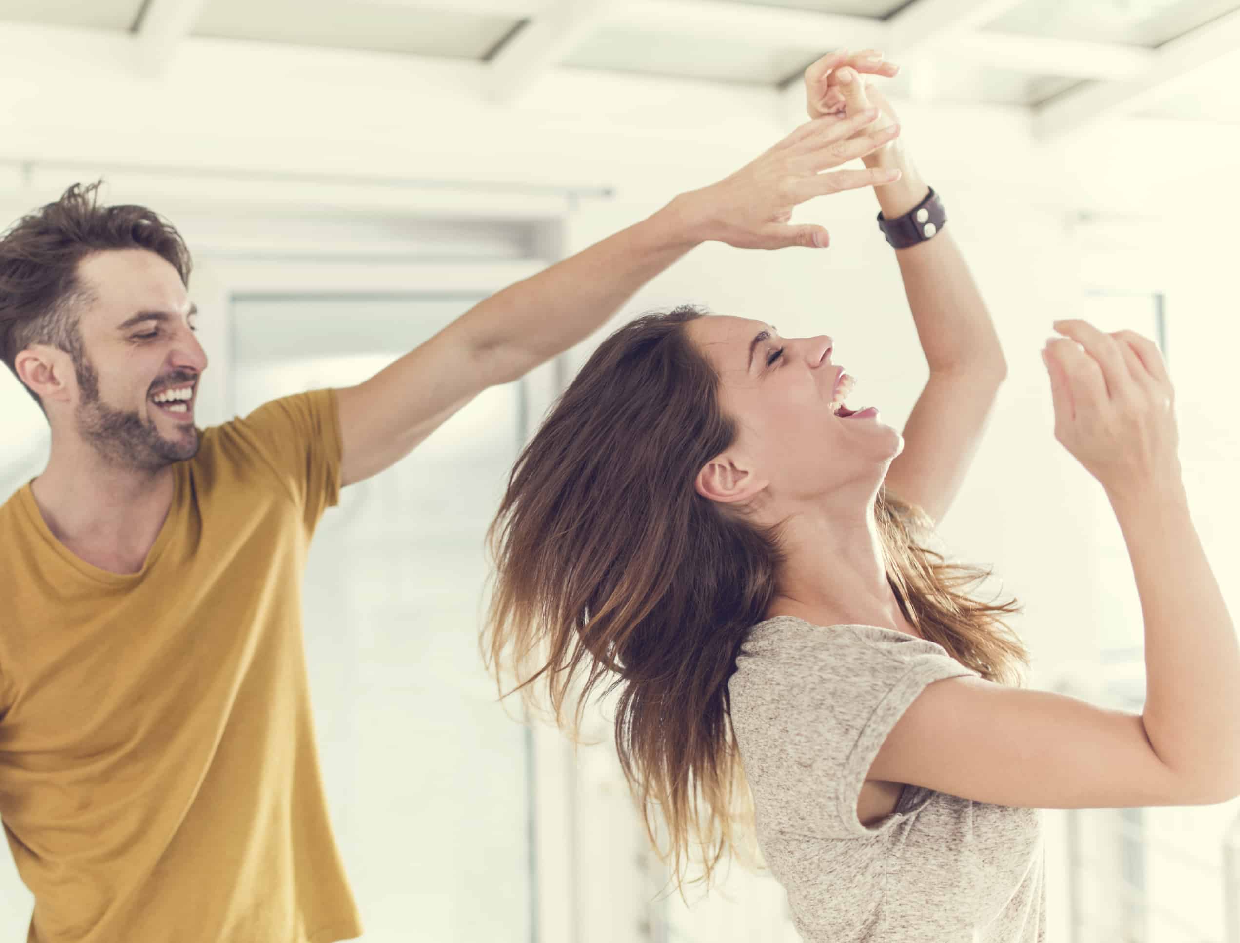 Happy young couple dancing at home and laughing.